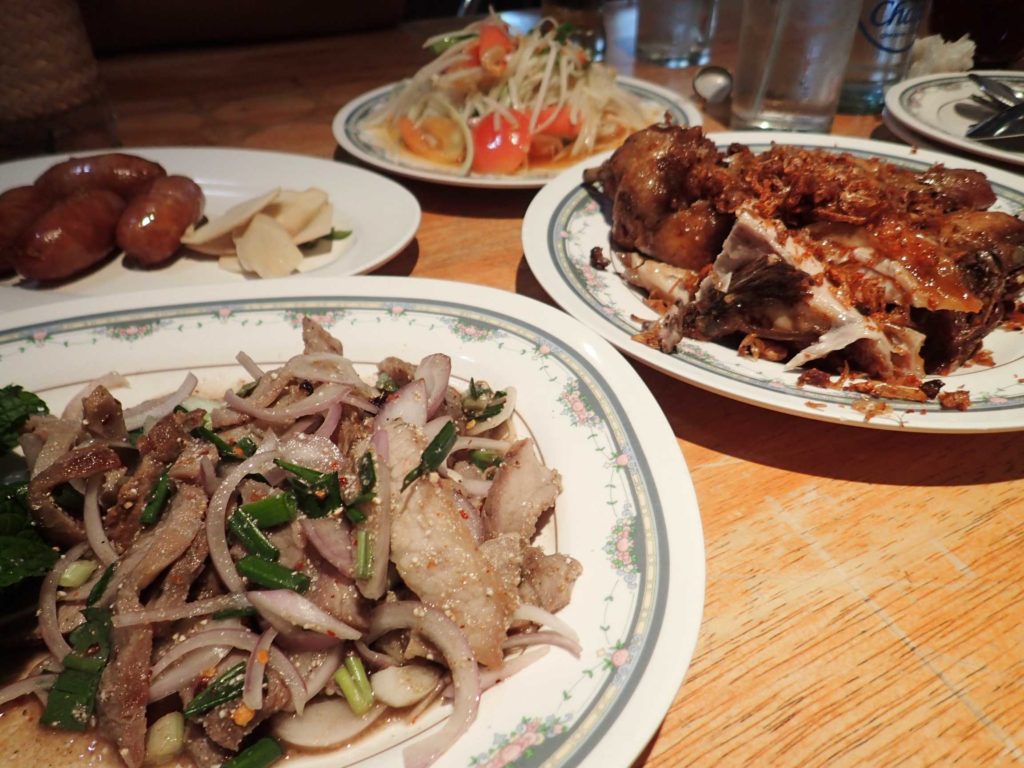 Nam tok moo (literally 'pork waterfall') in the foreground, garlic pork sausages, som tam (spicy papaya salad), and the famous Polo Fried Chicken