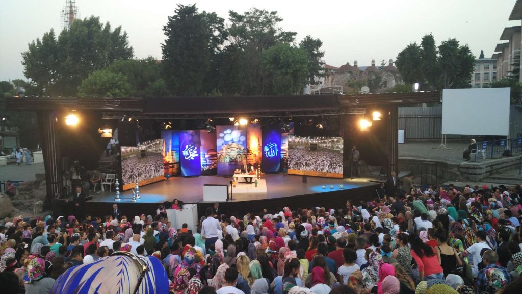 A man who seemed to be doing an iftar (sundown feast) television broadcast had attracted a large audience. He would occasionally take questions from the crowd.